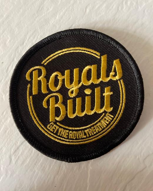 Round black embroidered patch with the gold Royals Built badge