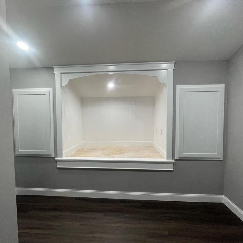 White built-in window-seat nook with an arched valance and a beadboard interior, between two panels