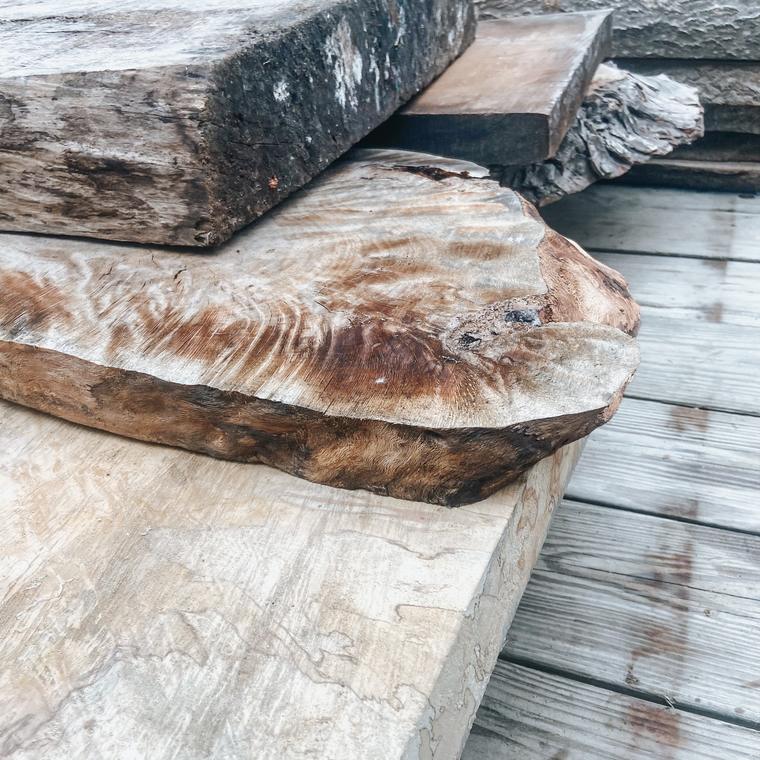 Stack of rough live-edge wood slabs with swirling figure