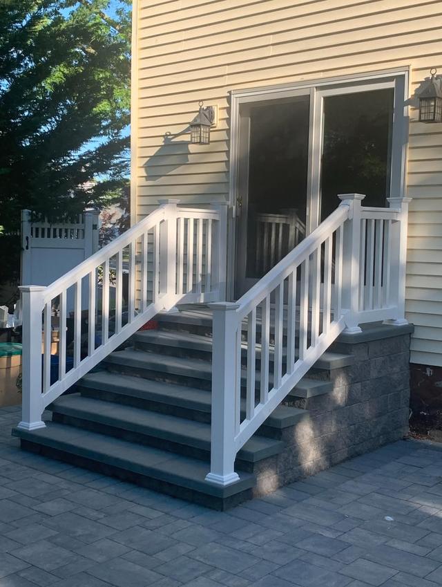White railings on both sides of stone steps leading up to a sliding door