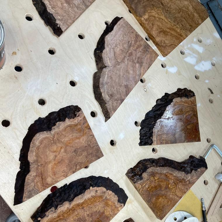 Finished live-edge corner shelves with dark natural edges and burl figure, laid on a bench