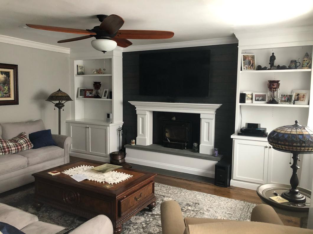Living room with white built-in shelves and cabinets on both sides of a fireplace, furnished with sofas